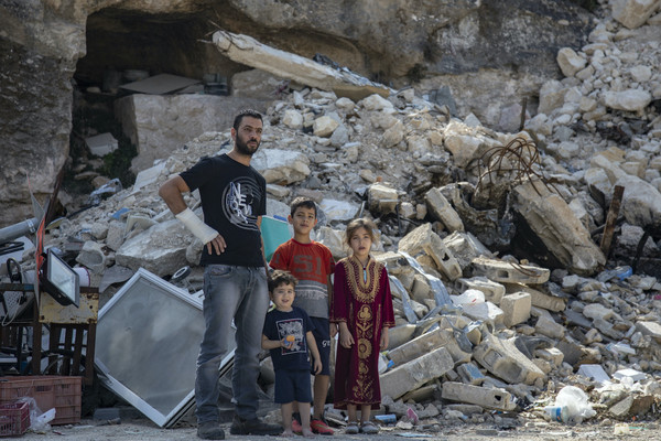 A Palestinian father stands with his children in front of the ruins of their home in Silwan, East Jerusalem, after it was demolished by Israeli authorities